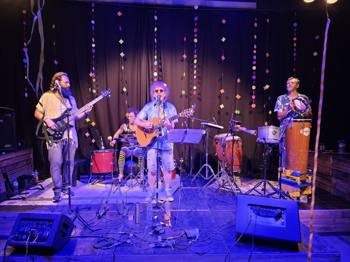 Show acústico solidário com músicos em um palco pequeno